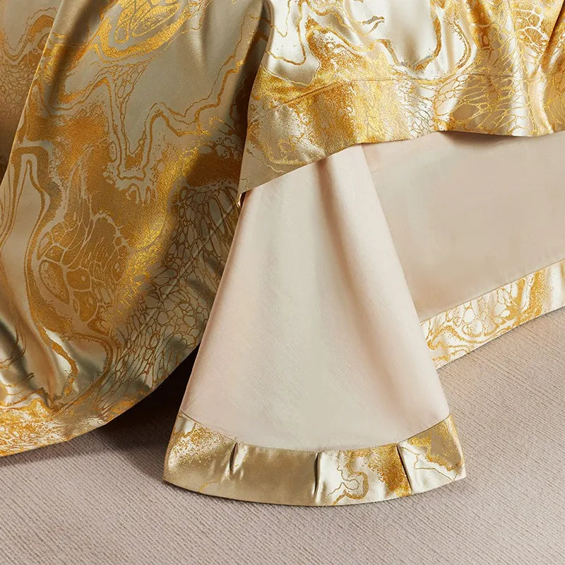Close-up of a gold marble jacquard duvet cover and white bed sheet finished with a wide patterned gold border – L&B