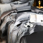 Dark gray luxury bedding set styled with a metallic jacquard duvet cover, layered pillows, and refined bedside details – L&B