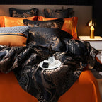 Close-up of a black and gold jacquard duvet cover showing the ornate woven pattern and burnt orange reverse fabric – L&B