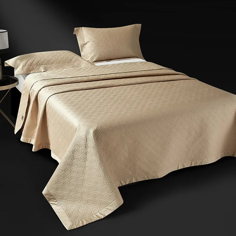 Champagne gold quilted bedspread layered over an abstract geometric duvet cover, LUSTRA GOLD – L&B
