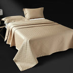 Champagne gold quilted bedspread layered over an abstract geometric duvet cover, LUSTRA GOLD – L&B