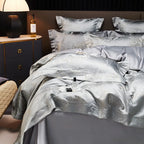 Luxury silver bedding set styled with a jacquard duvet cover, layered gray pillows, and smooth Egyptian cotton sheets – L&B