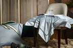 Sky blue damask bedding draped over an accent chair to showcase its jacquard pattern and fluid satin finish – L&B