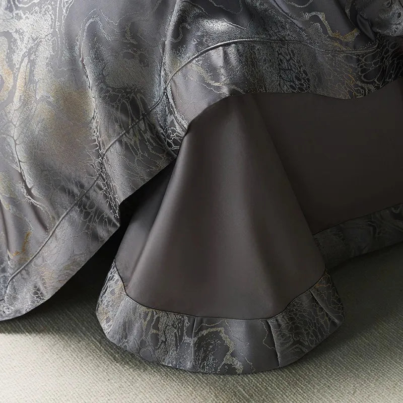 Dark gray jacquard duvet cover draped over a smooth Egyptian cotton sheet with a tailored ruffle border – L&B