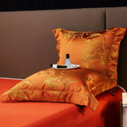 Ornate rust orange pillow sham and folded jacquard duvet cover displayed against a solid orange sheet – L&B