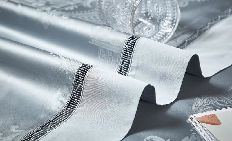 Close-up of a light blue pillow sham and duvet cover with braided edging and damask jacquard detailing – L&B