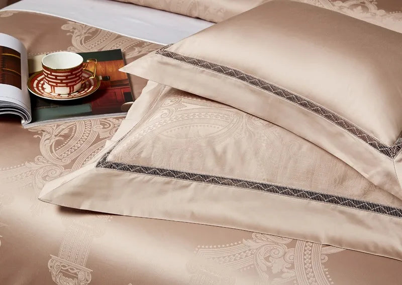 Layered beige pillow shams with tonal braided trim and a smooth champagne satin finish - L&B