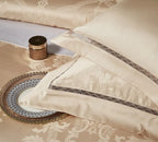Champagne gold pillow shams with tonal braided trim and a smooth satin jacquard finish - L&B