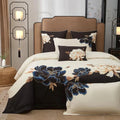Blue floral embroidery on a black and ivory duvet cover creates a bold botanical focal point on an elegantly styled bed – L&B