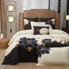 Blue floral embroidery on a black and ivory duvet cover creates a bold botanical focal point on an elegantly styled bed – L&B