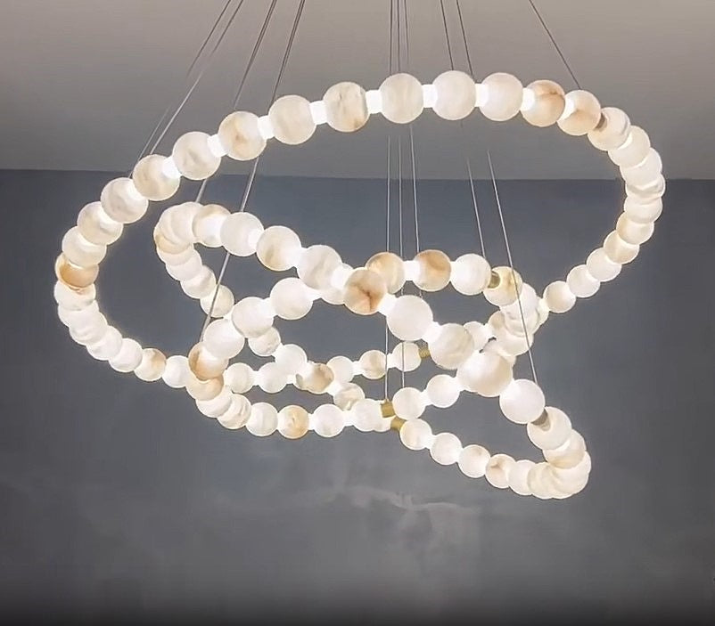 Illuminated three-tier alabaster globe ring chandelier with natural stone spheres, brass details, and adjustable suspension – AURELIA